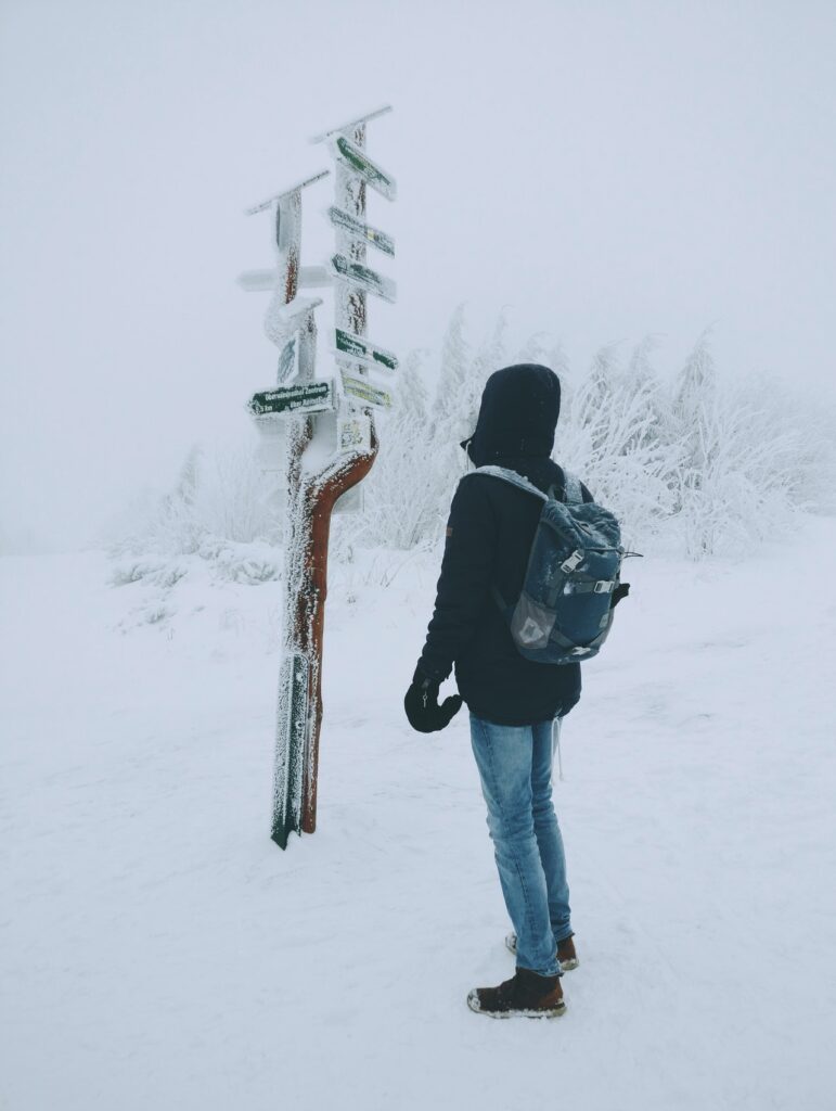 traveller looking at snowy signposts